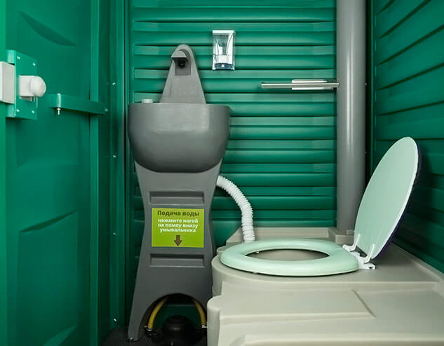 Накопительный бак для отходов и умывальник с ножной помпой, установленые внутри зелёной туалетной кабины «Люкс».
