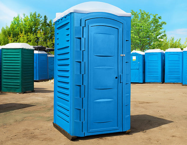 Синяя туалетная кабина «Евростандарт» в окружающей среде, вид спереди.
