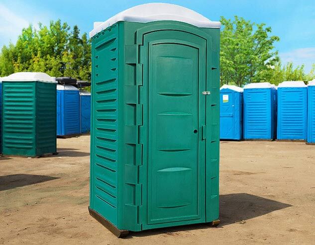 Зелёная туалетная кабина «Евростандарт» в окружающей среде, вид спереди.
